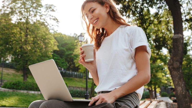woman sitting on bench in green park on summer day