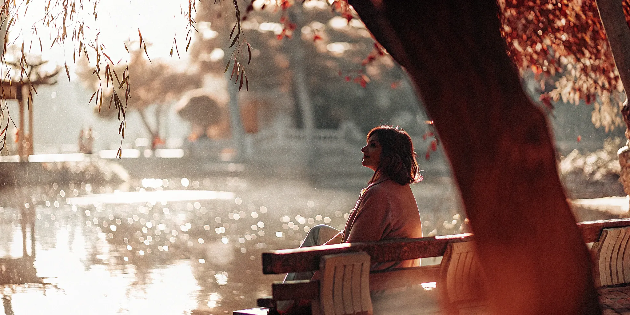 A woman sits alone on a park bench, contemplating the symptoms of anxiety in women.