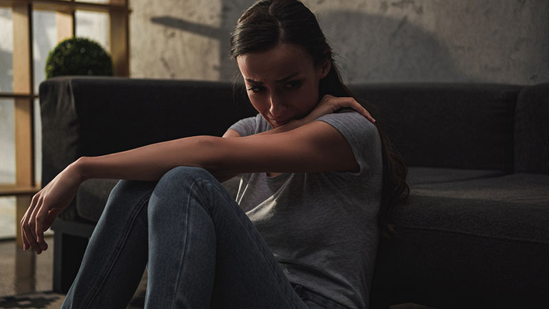 Depressed woman crying and sitting on floor