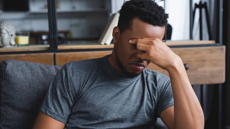 man sitting on sofa experiencing headache