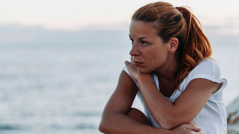 Young woman feeling sad by the sea