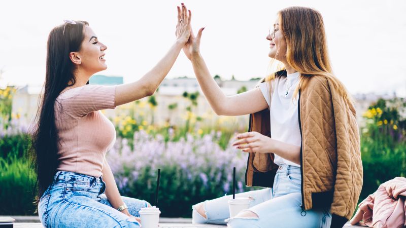 two happy students giving five to each other
