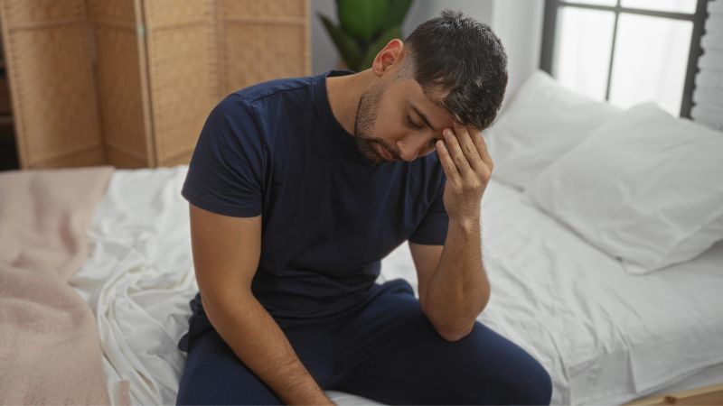 man sitting on bed in bedroom with dizziness