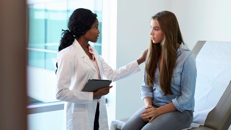 Female doctor consulting teenage patient