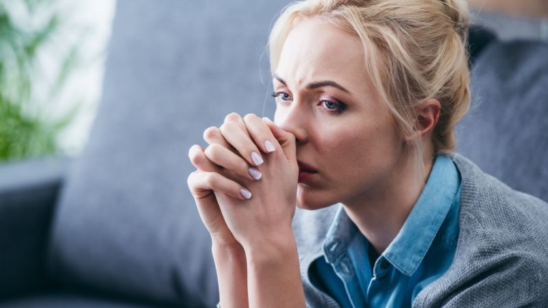 upset woman with folded hands sitting at home