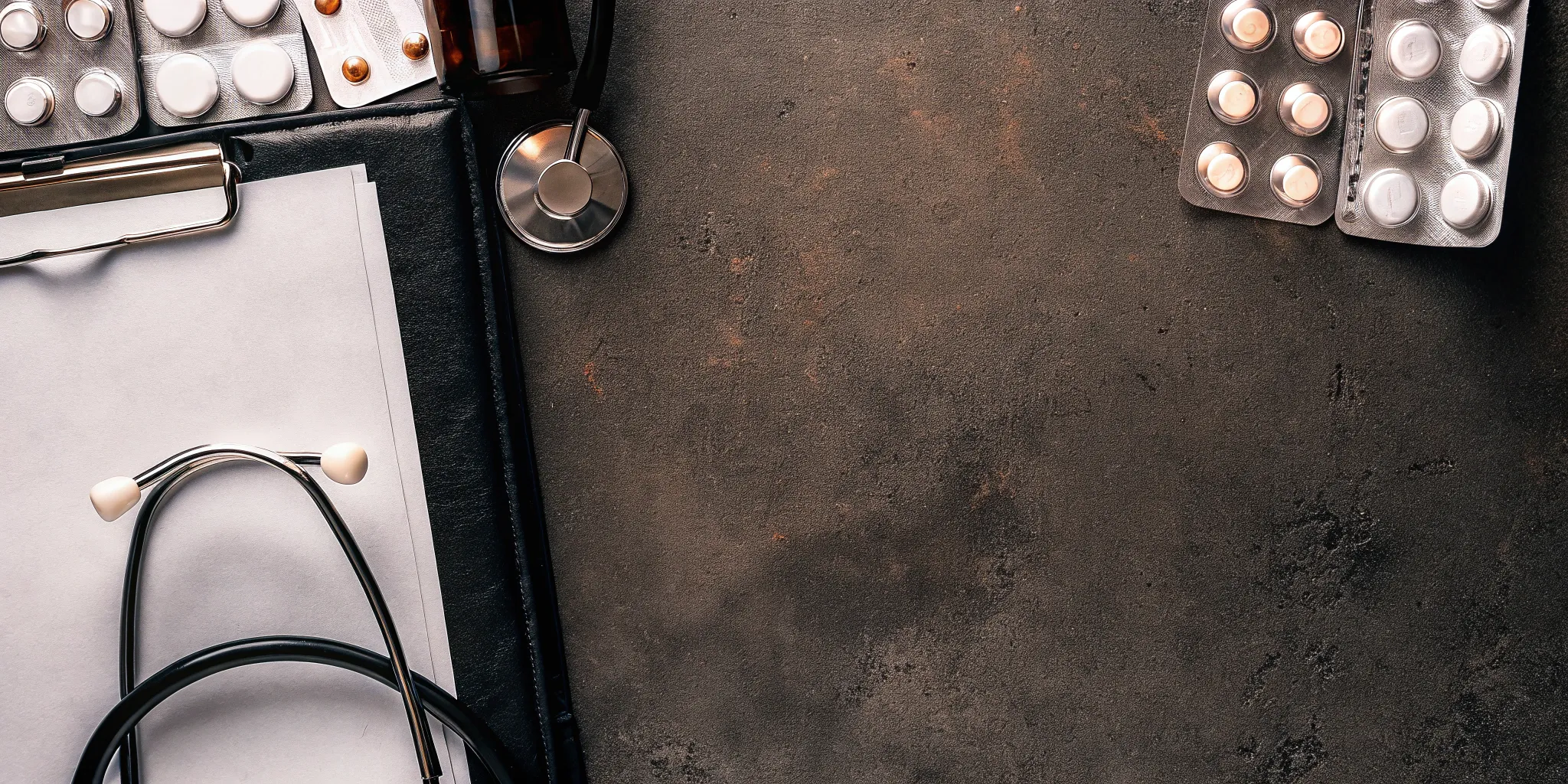 A medication management provider's desk with a clipboard, stethoscope, and medication.