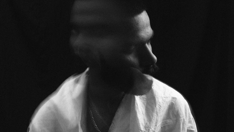 Depressed young man with blurred head in dark room