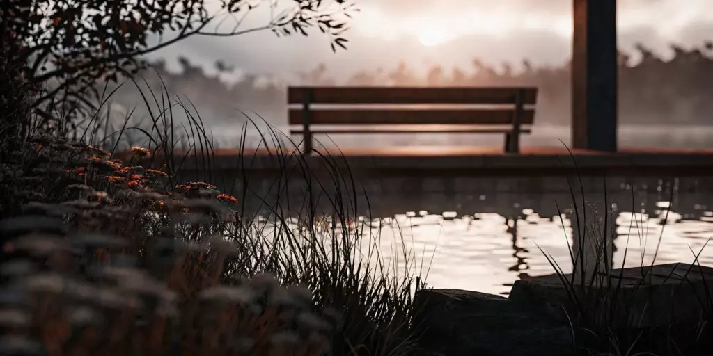 A bench by a calm pond at sunrise, a peaceful way to calm an anxiety attack.