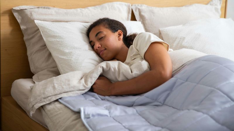 A woman sleeping in a bed with a blanket