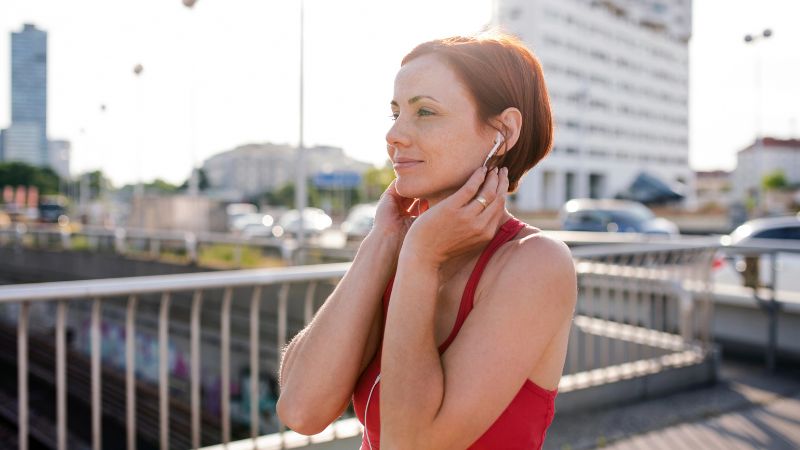 A young woman runner with earphones in city