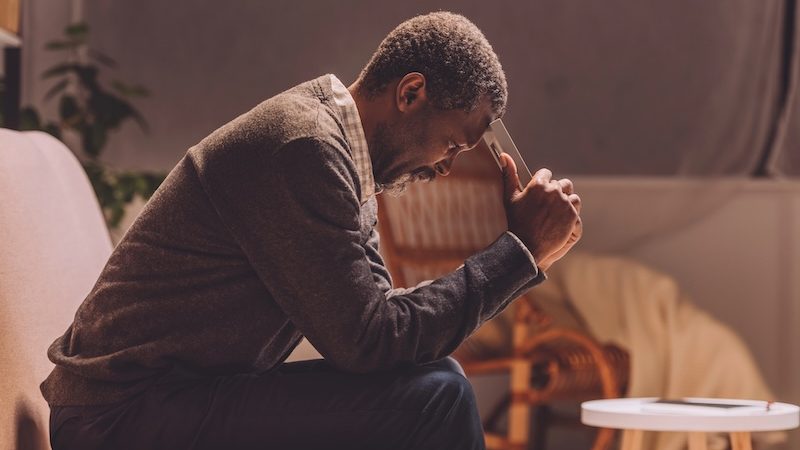 Depressed african american man sitting on sofa
