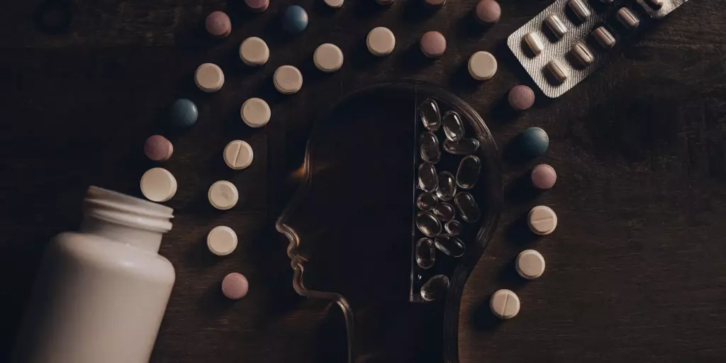 Common mental health tablets and pills arranged around the outline of a human head.