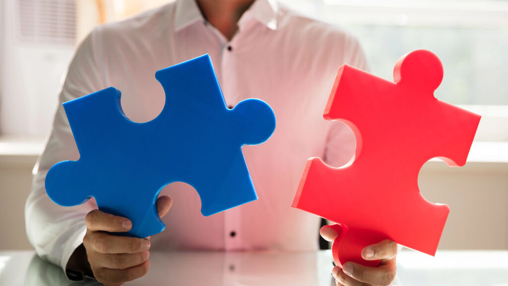 hand connecting two colorful jigsaw puzzles