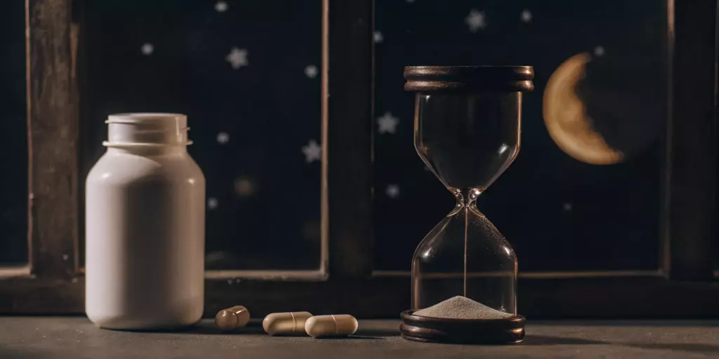 An hourglass and a pill bottle highlighting the long-term side effects of psychiatric drugs.