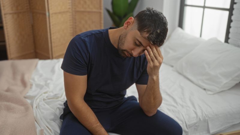 man looking down with a hand on his forehead
