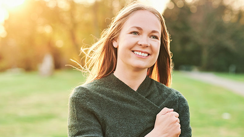 smiling young woman in spring park at sunset