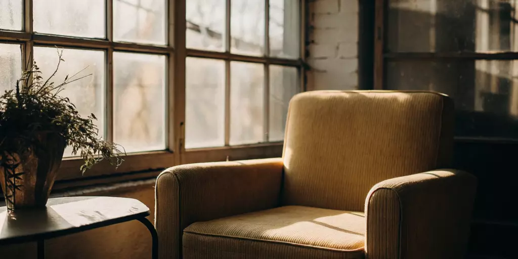 A comfortable chair in a sunlit room for someone considering the pros and cons of TMS therapy.