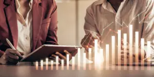 Two professionals discussing the cost of TMS for MDD with a financial bar graph.