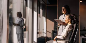 Woman in a TMS therapy chair for OCD treatment, with a clinician holding a tablet nearby.