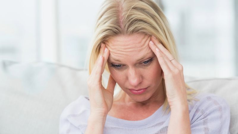 woman with migraine rubbing her temples