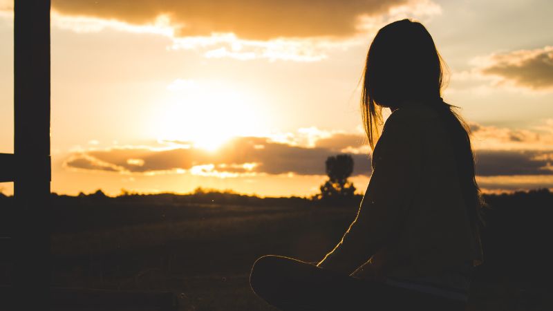 woman meditating at sunset