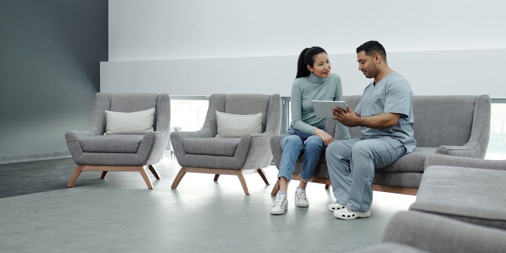 A doctor in scrubs consulting a female patient